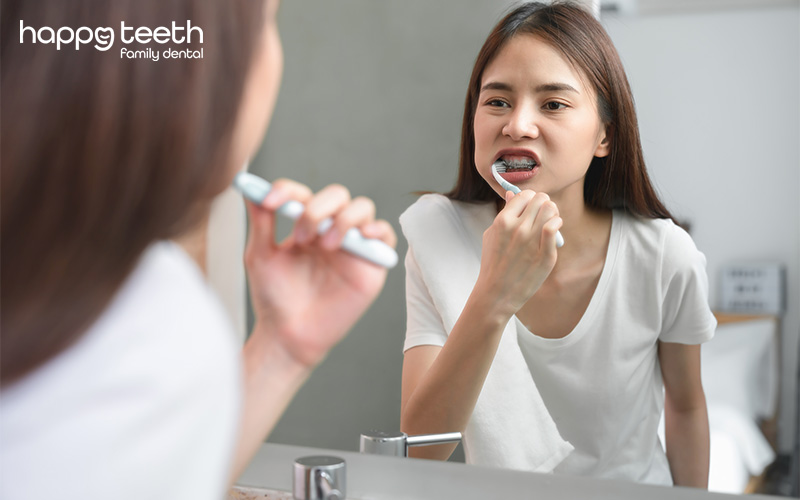 Woman brushing her teeth in front of a mirror for daily dental care Woman brushing her teeth in front of a mirror for daily dental care.