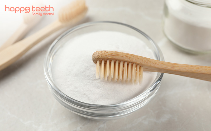 Wooden toothbrush resting on a bowl of baking soda for natural teeth whitening Wooden toothbrush resting on a bowl of baking soda for natural teeth whitening
